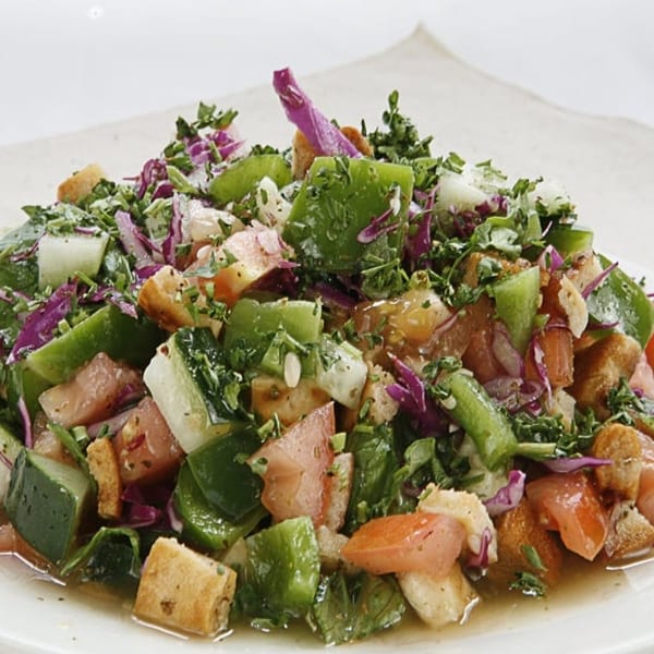 Close-up of a vibrant Fattoush salad with fresh vegetables, herbs, and toasted bread pieces.
